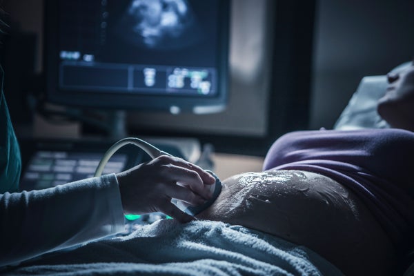 A medical technician performs a sonogram on a pregnant patient